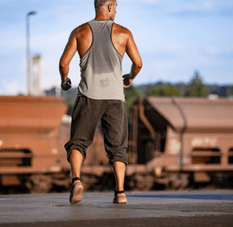 a man in a tank top running on a train track