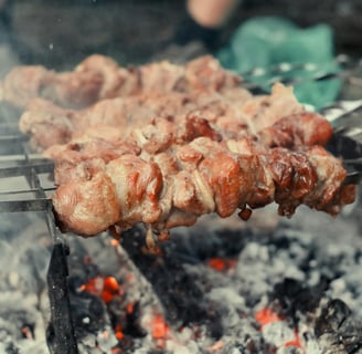 a person is cooking on a grill with meat and vegetables