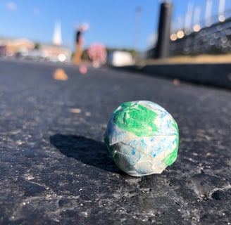 a model of the earth sitting on the ground with students and school in the background