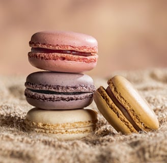 4 macarons dont trois empilés sur une toile de jute et un fond marron clair