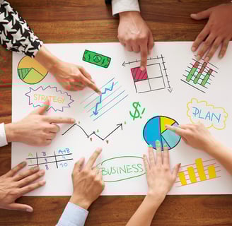 a group of people sitting around a table with a paper board with a diagram of