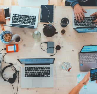 a group of people sitting at a table with laptops and cell phones