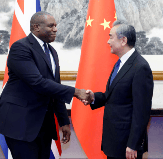 two men shaking hands in front of a chinese flag