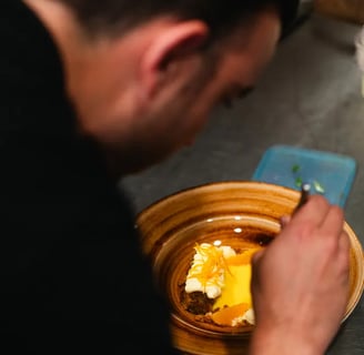 Nico, chef de Es Mestral, finalizando la presentación de un postre de naranja con crema y ralladura cítrica en la cocina del