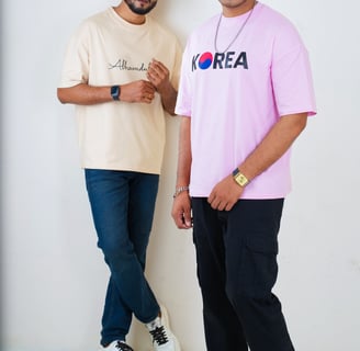 two men standing next to each other in front of a white wall