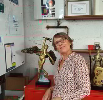 Photo de l'artiste sculpteure Lode dans son atelier posant à côté de ses sculptures