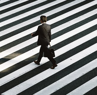a man in a suit and tie walking across a crosswalk