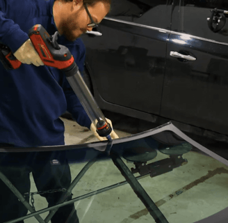 man caulking windshield in the shop