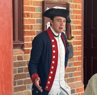 a man in a colonial era uniform standing in front of a brick wall