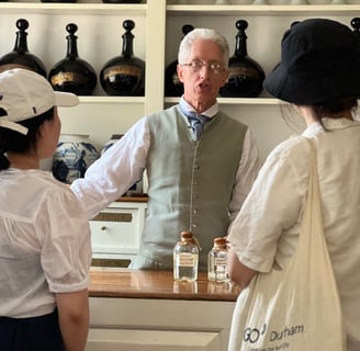 Man in colonial costume serving customers in a shop