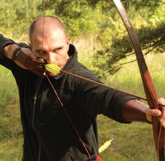 traditional archery technique a man in black shirt drawing a bow