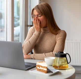 a woman sitting at a table with a laptop and a cup of coffee