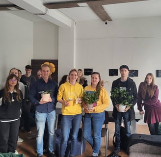 Orchidėjų laboratorijos renginio dalyviai sustoję kartu su lektore Vilte. Rankose laiko orchidėjas.
