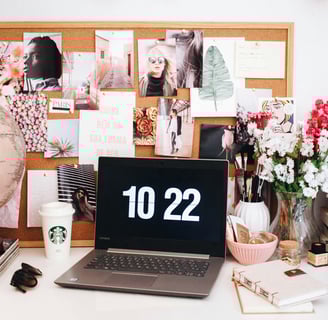 a laptop computer sitting on a desk with a clock on it