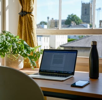 a laptop computer sitting on a desk with a phone and a bottle of water