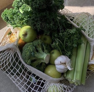 Assortment of fruits and vegetables: garlic, parsley, kale, and apple