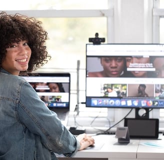 a woman sitting at a desk with a computer and a laptop about to perform a remote online notarization