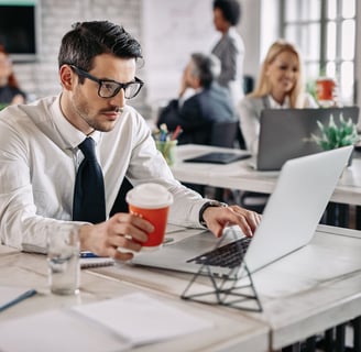 a man in a tie and a tie is sitting at a table with a cup