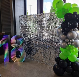 Silver shimmer wall with marquee number and balloons for an 18th birthday at Beenleigh Distillery.