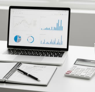 Mesa branca mostrando um caderno com caneta, calculadora, uma xicara e um computador com graficos