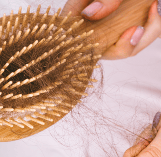 Spazzola in legno con capelli caduti, rappresentazione della perdita di capelli e dell'importanza de