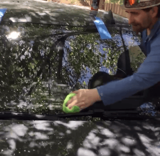 A Technician is finishing a windshield replacement and wiping down the windshield.