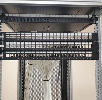 Baie informatique câblée proprement avec panneaux de brassage RJ45 et câbles réseau organisés, installation réalisée par Domi