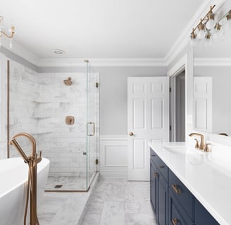 Luxury bathroom remodel with marble tile, navy vanity, and gold fixtures in London, Ontario.