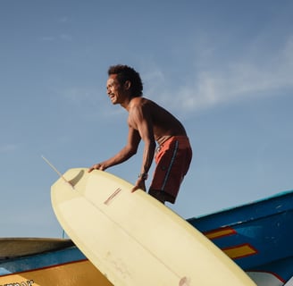 Surfer with a yellow board on boat at a surf school in Kuta Lombok. He is enjoying a surf lesson.