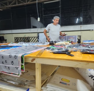 Imagem da mesa de corte da Persona estamparia, com vários materias e produtos sobre a mesma.