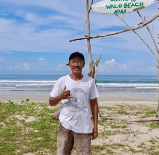 Darus, owner and manager of Afulu Surf Resort, smiling in front of the resort.