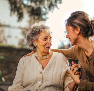 A young carer smiling and holding hands with an elderly woman