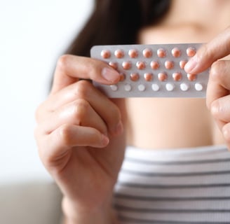 a woman holding a pill pack of pills