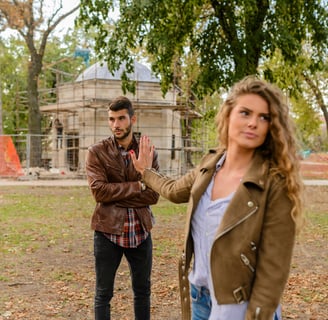 A couple sitting apart, with one partner looking distressed while the other avoids eye contact, symb