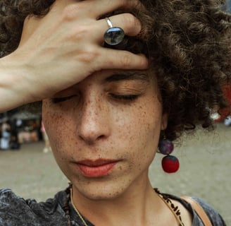 A close-up of a stressed person looking at the mirror, noticing acne breakouts and hair thinning. Th