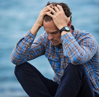 a man sitting on a bench with his hands on his head