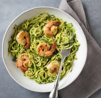 a bowl of pasta with shrimp and pesto sauce