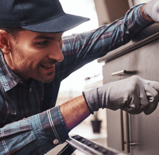 a man in a hat and gloves is putting something in the oven