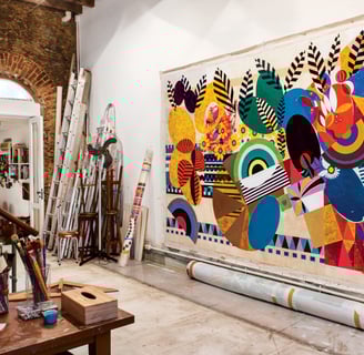 Ateliê de Beatriz Milhazes, colorido e cheio de obras e materiais de arte.