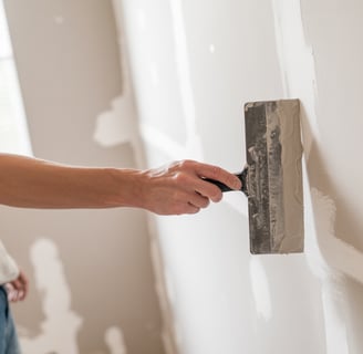 man applying drywall mud to a wall with a mud knife