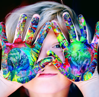 Un enfant joyeux en art-thérapie avec des mains colorées pour créer son œuvre d'art