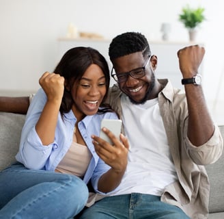a man and woman sitting on a couch with a cell phone