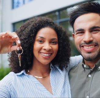 A happy family holding house keys in front of a new home.