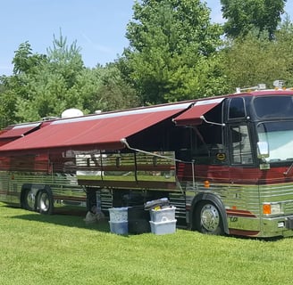 a red Prevost bus parked in a grassy field