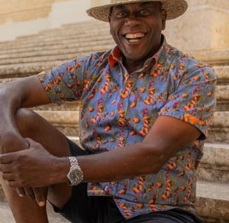 A man in a hat sits on some limestone steps.