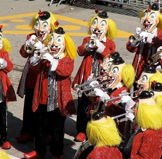 Figures dressed as clowns, playing trumpets. 