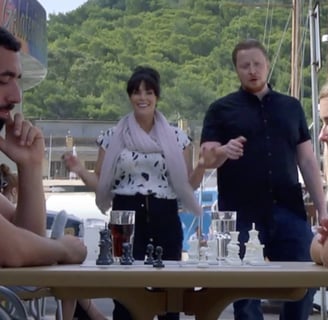 a man and woman sitting at a table with chess pieces.