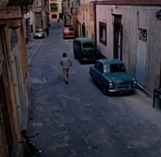 A man walking through a narrow street.