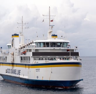 Gozo Channel Ferry in a flat grey sea, against a cloudy sky.