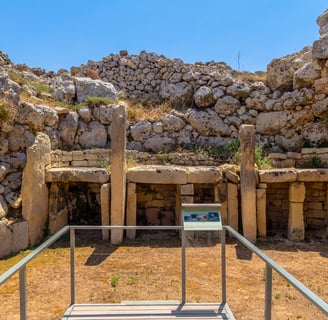 Ggantija Temples. A semi-circle limestone rubble wall surrounds three altar slabs.